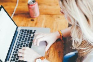 femme sur un pc posé sur un bureau avec une canette à côté